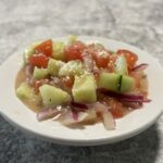 Crisp Apple Honey Cucumber Salad in a bowl, featuring cucumbers, tomatoes, onions, and a homemade apple honey vinaigrette.